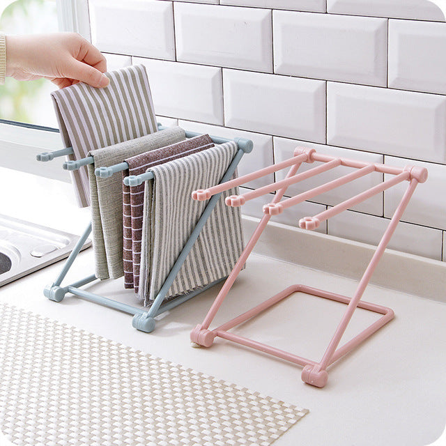 Foldable vertical dishcloth drying rack standing on a clean kitchen countertop holding two cloths.