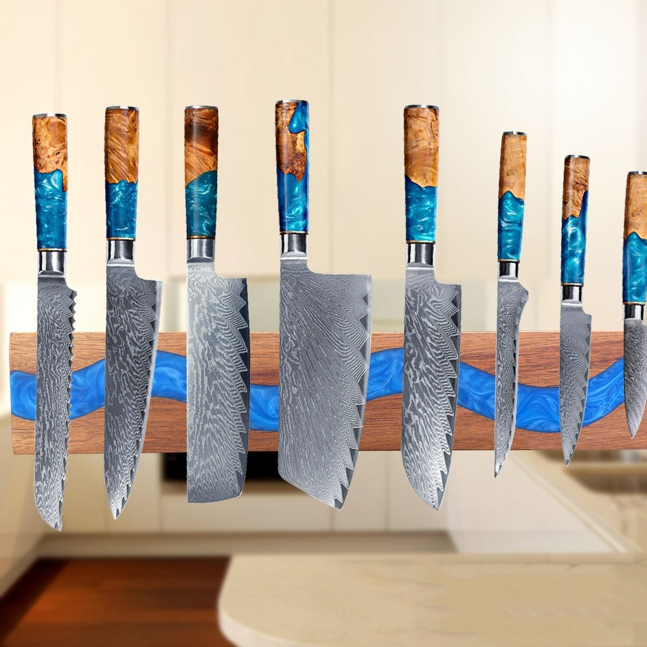 Wall-mounted magnetic resin knife holder strip securely holding various stainless steel chef knives.